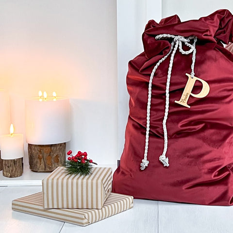 Soft Velvet Santa Sacks in colour Ruby by a candle lit fireplace